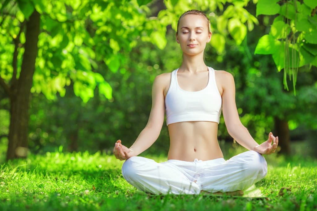 Yoga outdoors. Woman meditating in lotus position zen gesturing. Concept of healthy lifestyle and relaxation